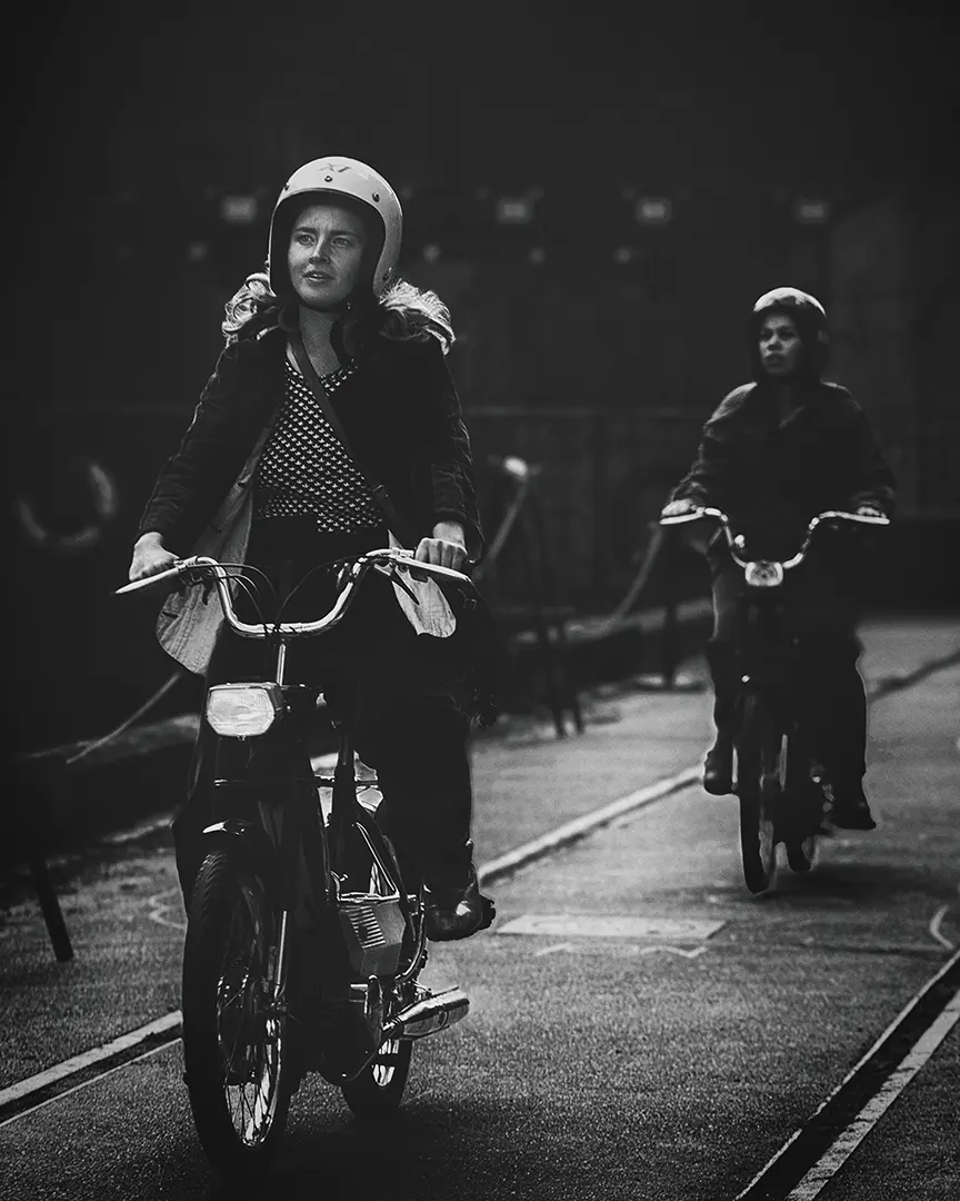 Cyklister bevæger sig gennem et mørkt byrum