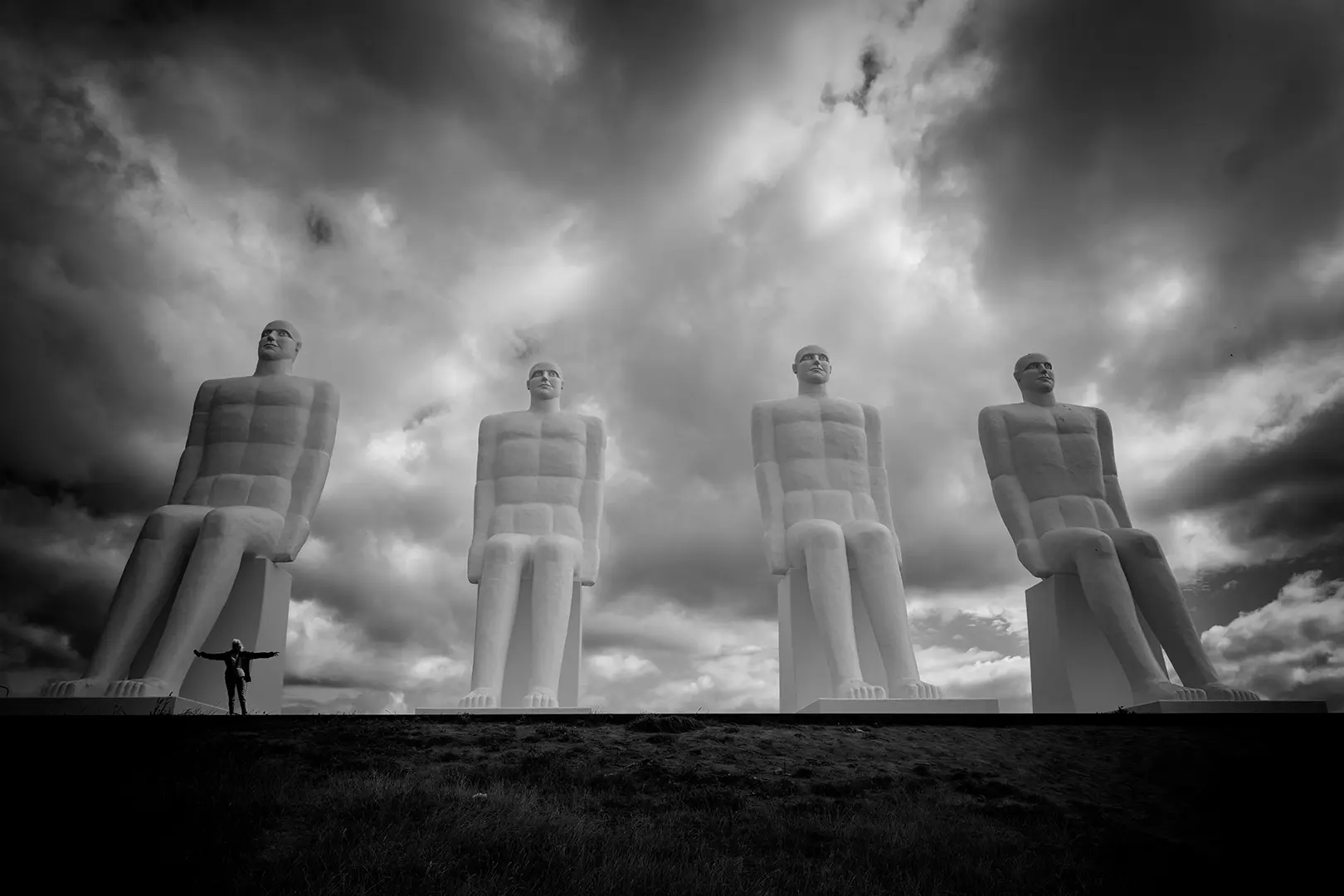 Fire monumentale figurer under en dramatisk himmel